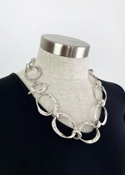 Linked Silver plated hoops on hoops create the beautifully made and easy to wear Lustra necklace. Large rustic hoops create a mid length necklace that is ideal when you want to add a sophisticated finishing touch to any outfit, work or play. The Lustra necklace is a modern statement piece you will reach for time and again. Secure with a single bar through a smaller hoop. One size only * Quality silver plated pewter – lead and nickel free * Length: 58cms, neck opening length 29cms